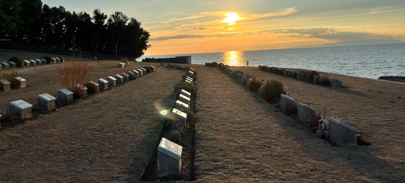 The sunsets over the sea and a CWGC cemetery on a Gallipoli beach.