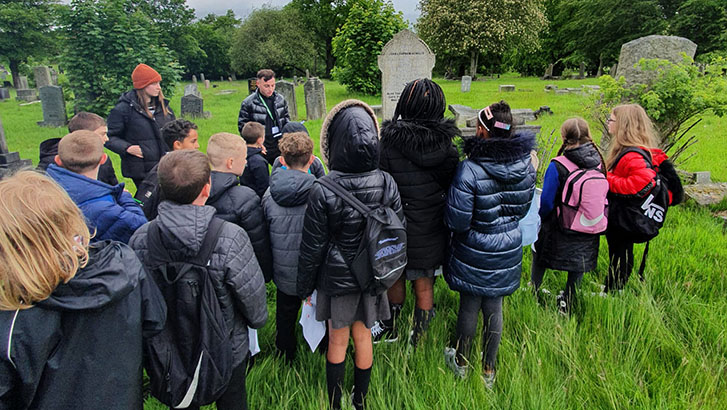 CWGC Tour Guides giving a talk to a group of schoolchildren in a cemetery
