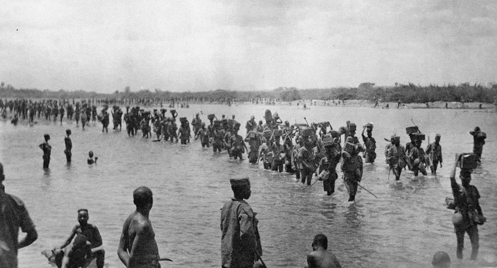 Sierra Leone Carrier Corps members crossing a low ford in a river.
