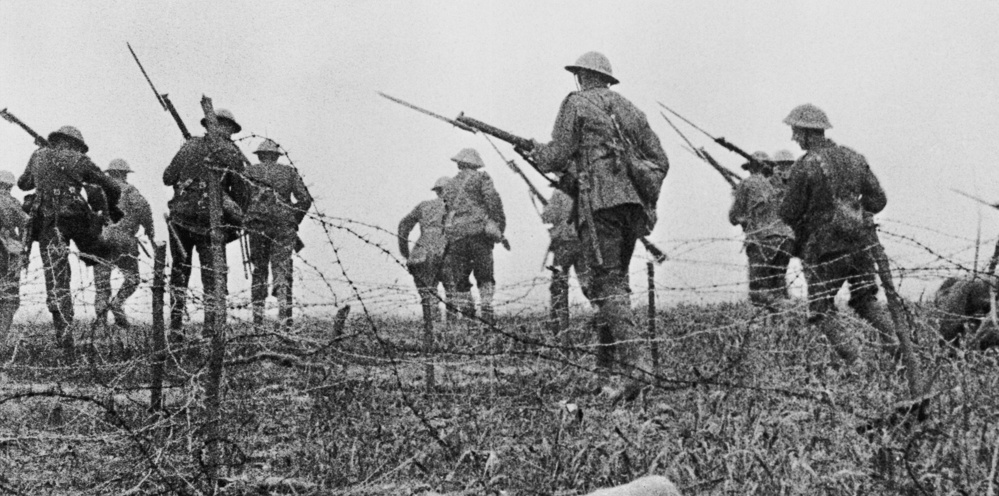 Soldiers marching through barbed wire holding rifles on the First Day of the Somme