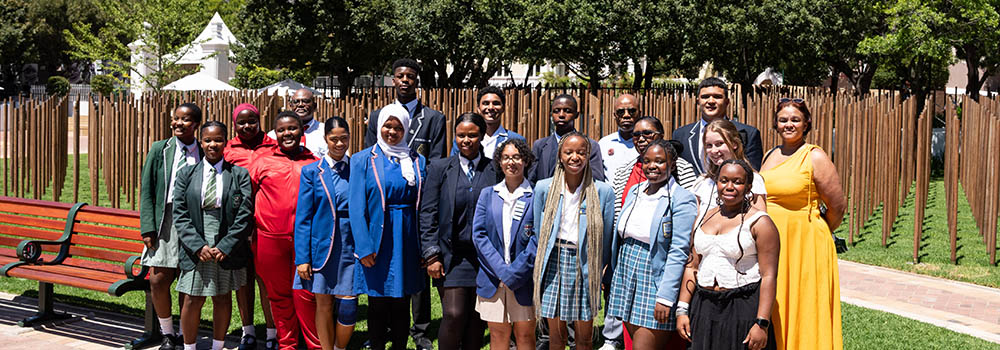 Class of secondary school pupils standing in front of the CWGC Cape Town Labour Corps Memorial.