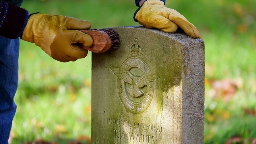 Close up of an Eyes On, Hands On volunteer cleaning a headstone