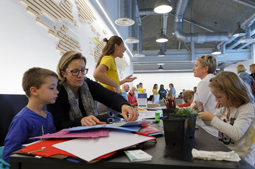 Adults and children working with paper around a table at the CWGC Experience